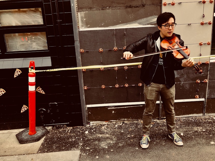 caption: Joe Kye plays the violin on the Ave in the University District after his interview at KUOW.
