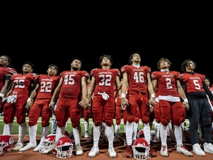 caption: FILE - The Lahainaluna High School football team hold hands to thank the fans after a game on Oct. 21, 2023, in Lahaina, Hawaii. Captains of the team whose town was destroyed by a deadly wildfire attended to Super Bowl in Las Vegas as guests of the NFL.