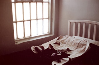 caption: A photo of what appears to be a straitjacket lying on a bed by a window. The image was found in the files of Northern State Hospital at the Washington State Archives in Olympia. 