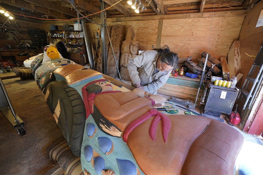 caption: Lummi Nation lead carver Jewell James works on the final details of a nearly 25-foot totem pole to be gifted to the Biden administration, Monday, April 12, 2021, on the Lummi Reservation, near Bellingham. The pole, carved from a 400-year old red cedar, will make a journey from the reservation past sacred Indigenous sites, before arriving in Washington, D.C. Organizers said that the totem pole is a reminder to leaders to honor the rights of Indigenous people and their sacred sites. 