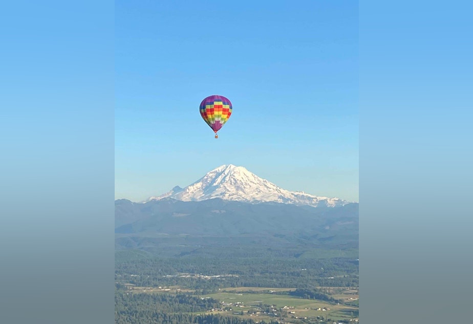 caption: The Happyanunoit balloon flies with Mount Rainier in the background.