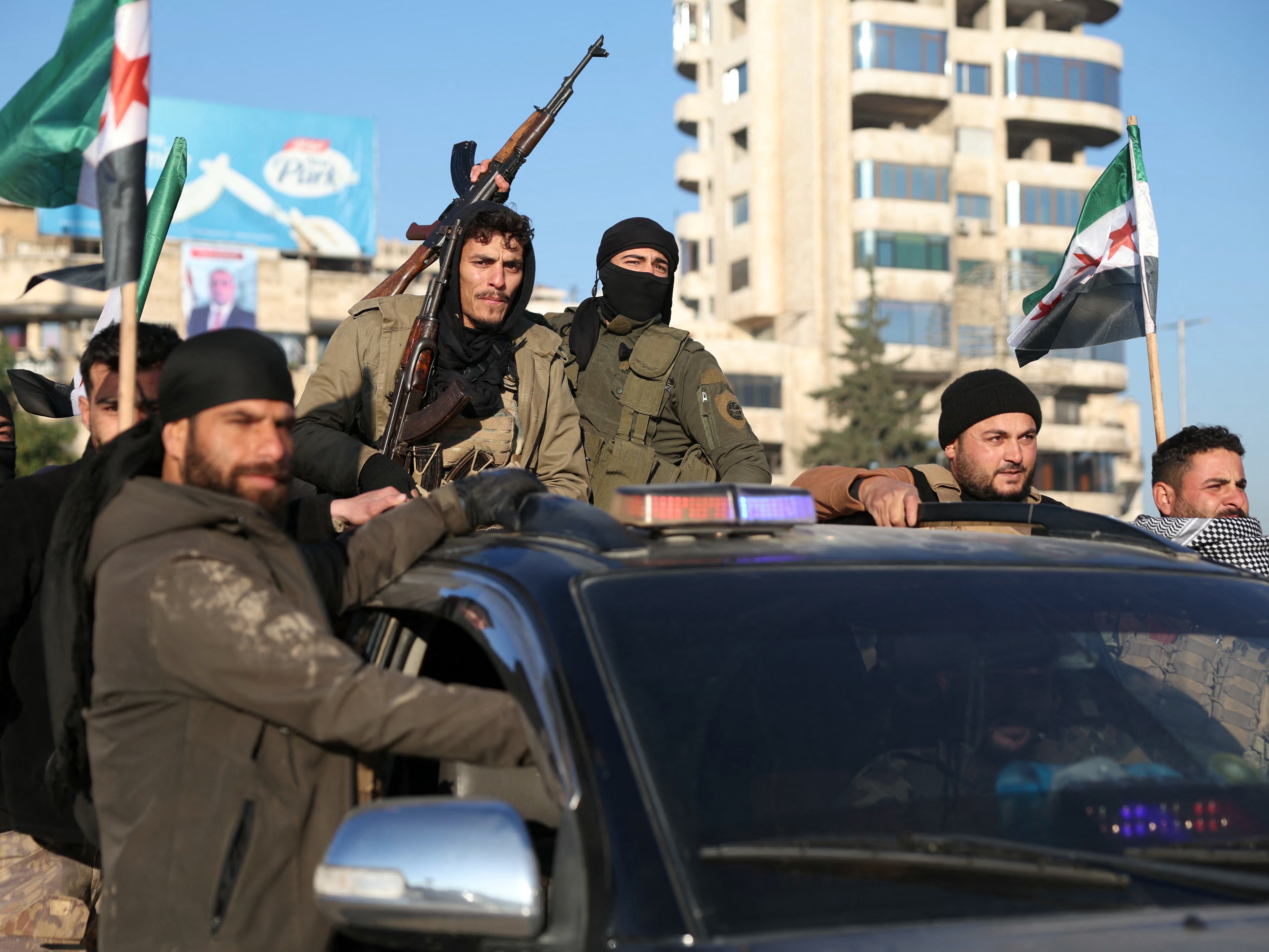 caption: Antigovernment fighters brandish their guns as they ride a vehicle in Syria's northern city of Aleppo on Nov. 30.