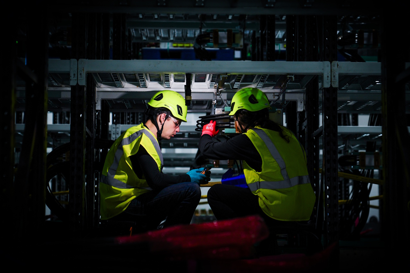 caption: Technicians work on capacitors at Helion. Capacitors absorb and discharge pulses of energy multiple times a second.  Helion has 2,000 capacitors on Costco-style shelves. They're designed to be quickly swapped out as capacitor technology gets better and better.