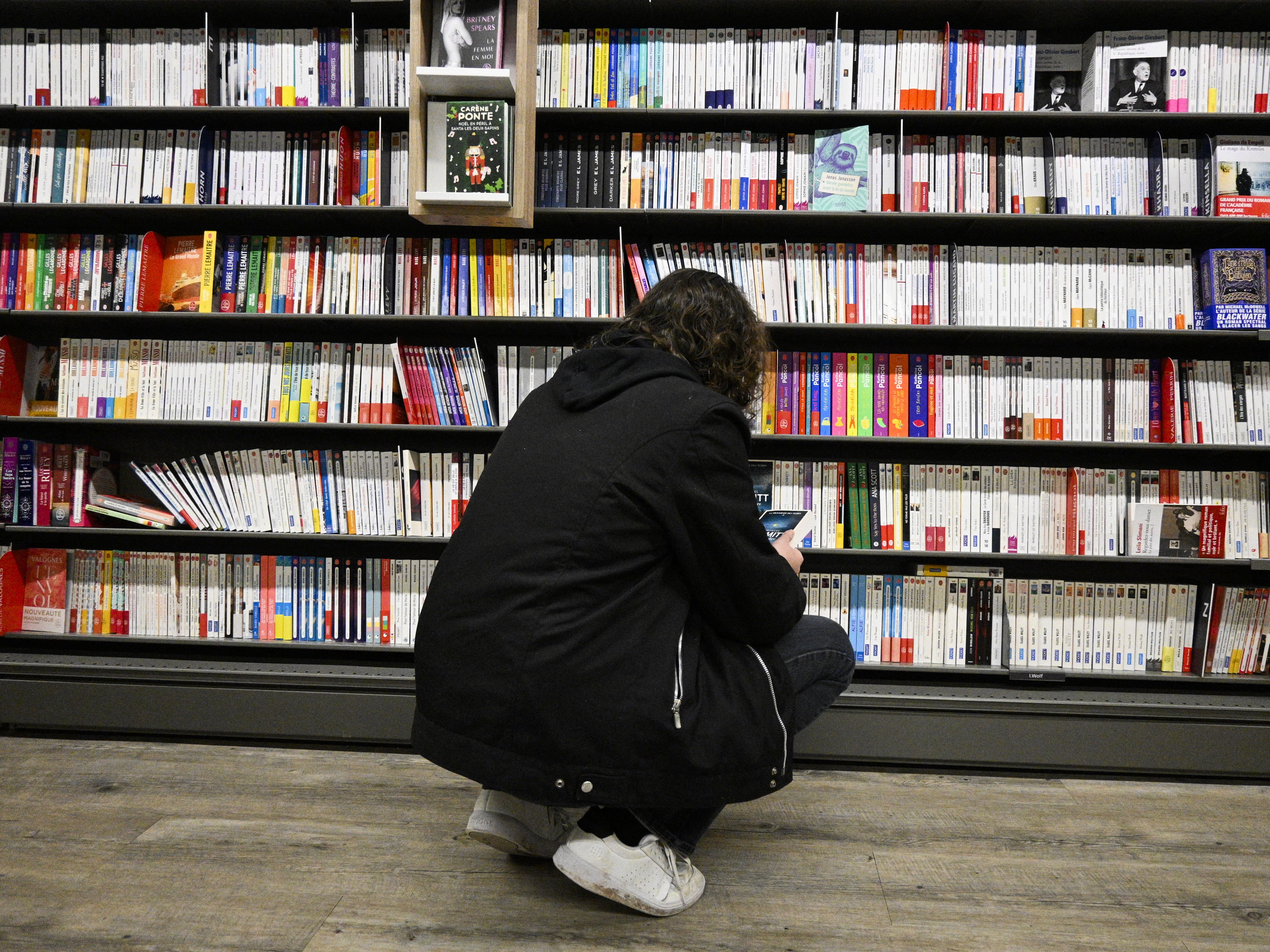 caption: A woman looks at books in a library in 2024.