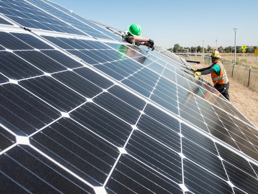 caption: To cut carbon emissions, President Biden announced an initiative to further cut the cost of solar installations, like this one being tested at the National Renewable Energy Laboratory in Colorado.