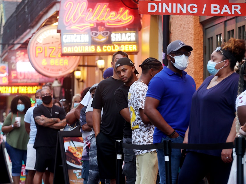 caption: People queue to enter a restaurant in New Orleans' French Quarter in early August.
