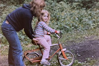 caption: Elaine Fichter teaches her youngest child, Lacy Lahr, how to ride a bike in the late 1980s.
