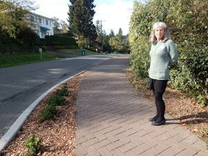 caption: Monica Sweet says cheaper asphalt sidewalks like this would be a good thing for neighborhoods that have been waiting decades for sidewalks.
