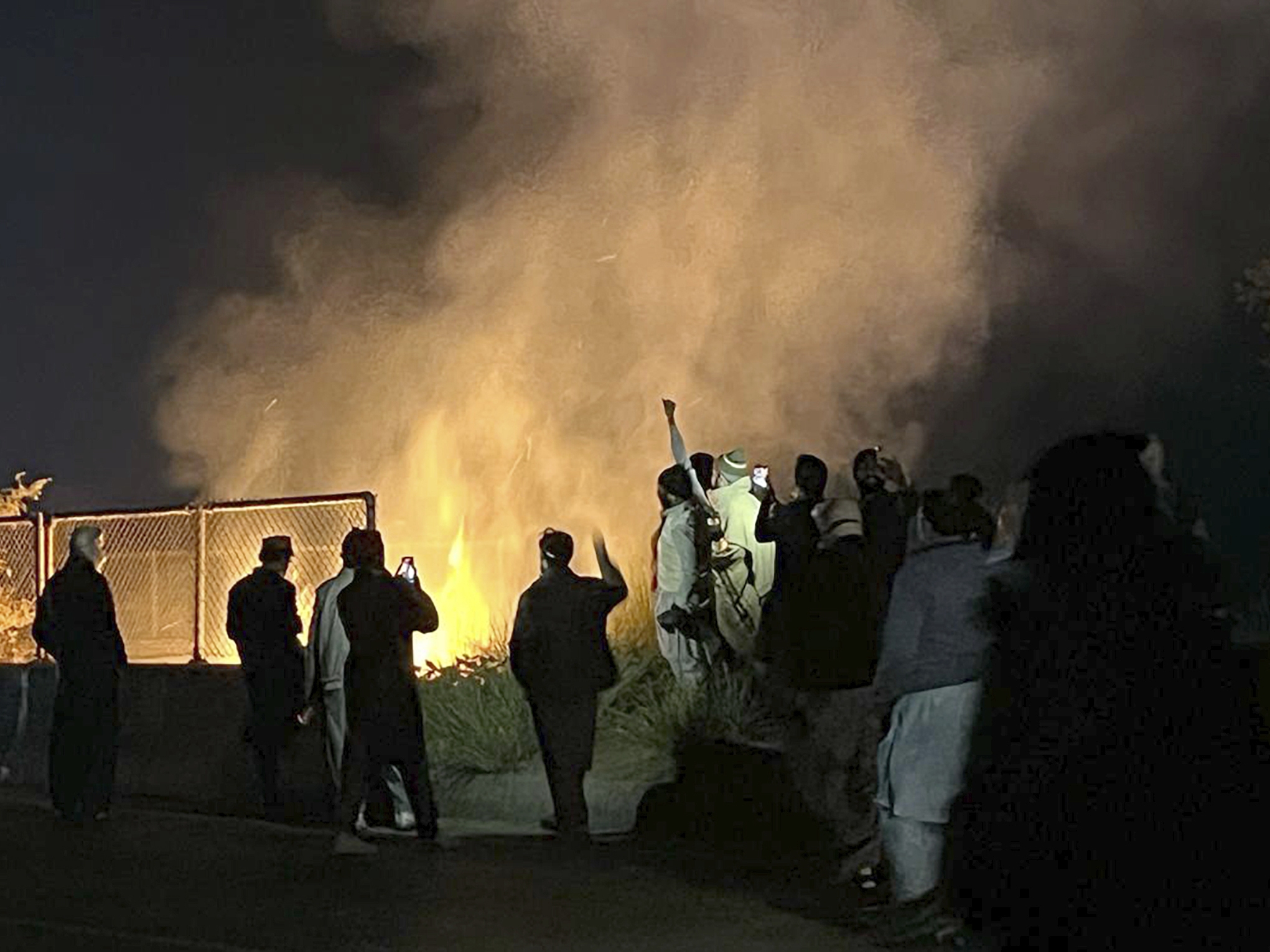 caption: Supporters of imprisoned former premier Imran Khan's Pakistan Tehreek-e-Insaf party, burn bushes to reduce the impact of tear gas shells fired by police officers to disperse them during a rally demanding Khan's release, at a motorway in Ghazi in Attock district, Pakistan on Sunday.