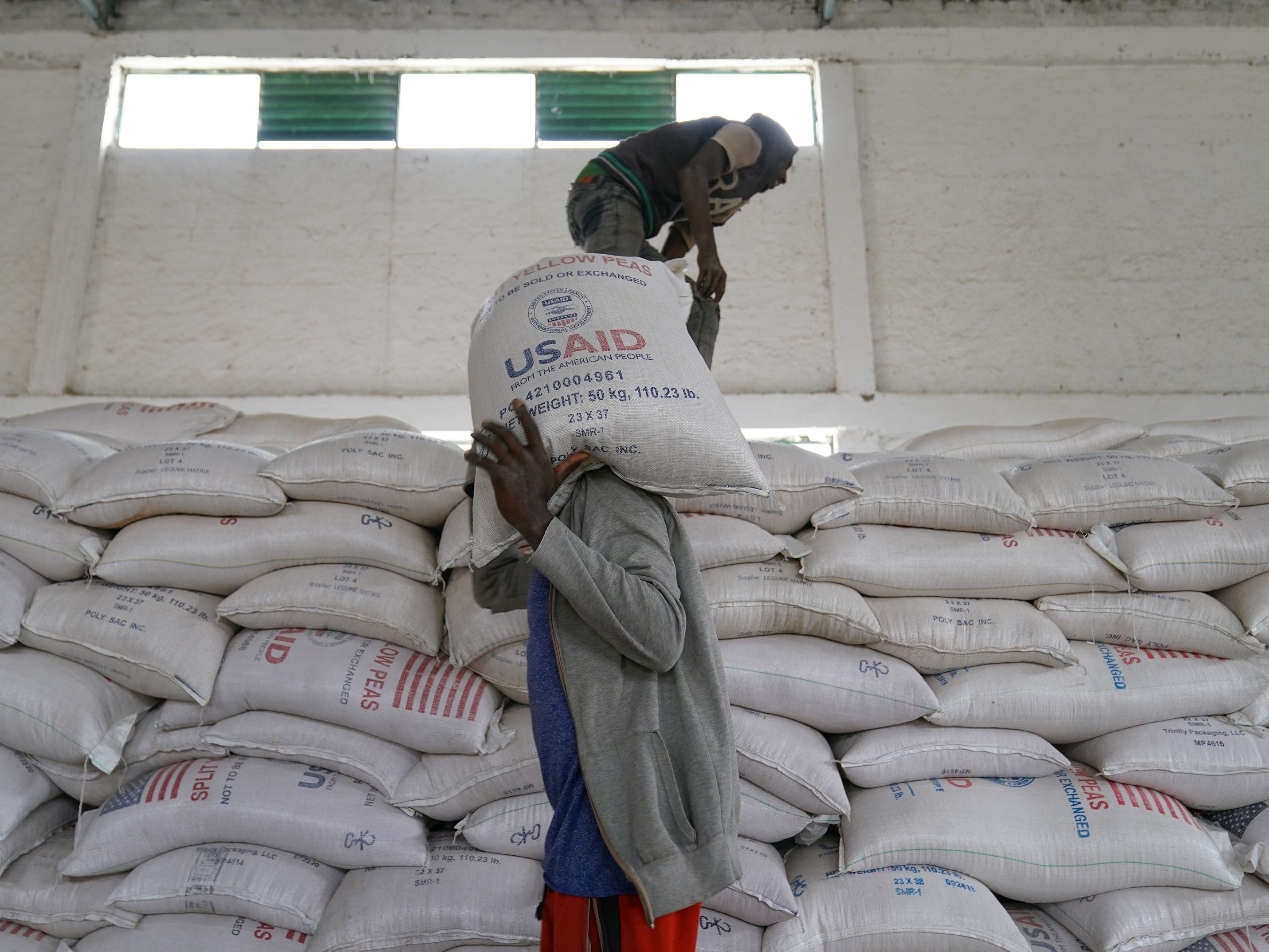 caption: Workers move bags of yellow lentils at an aid operation run by USAID, Catholic Relief Services and the Relief Society of Tigray in Mekele, Ethiopia, on June 16, 2021.