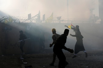 caption: Protesters and militia members throw stones toward the U.S. Embassy in Baghdad on Tuesday.