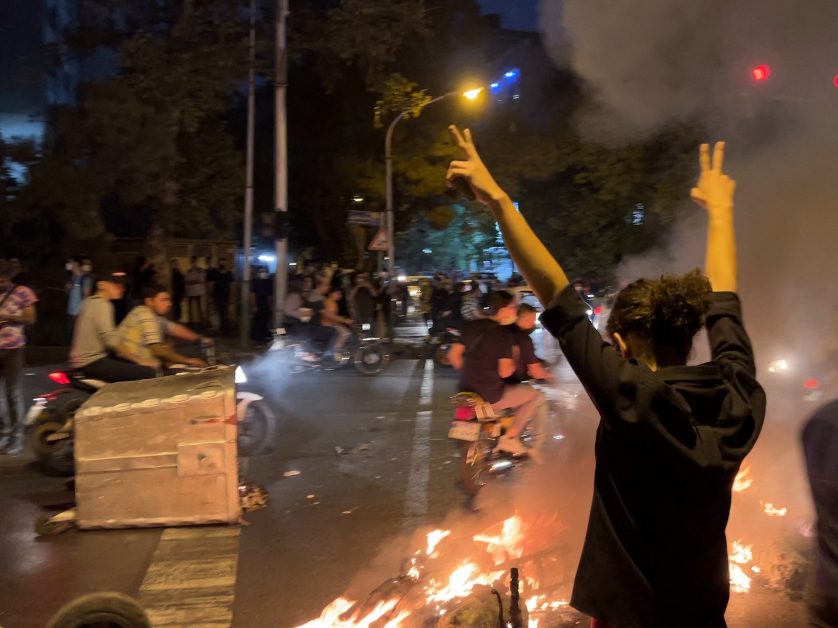 caption: A picture obtained by AFP outside Iran shows shows a demonstrator raising his arms and makes the victory sign in Tehran on Monday during a protest for Mahsa Amini, a woman who died after being arrested by the Islamic republic's morality police.