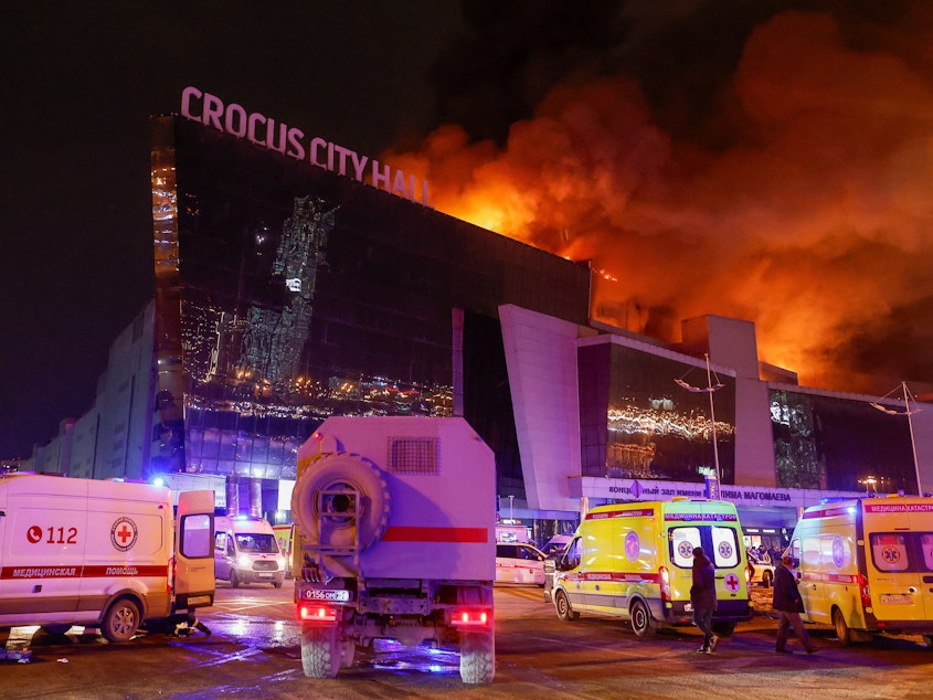 caption: Vehicles of Russian emergency services are parked near the burning Crocus City Hall concert venue, following a reported shooting incident, outside Moscow, Russia, March 22.