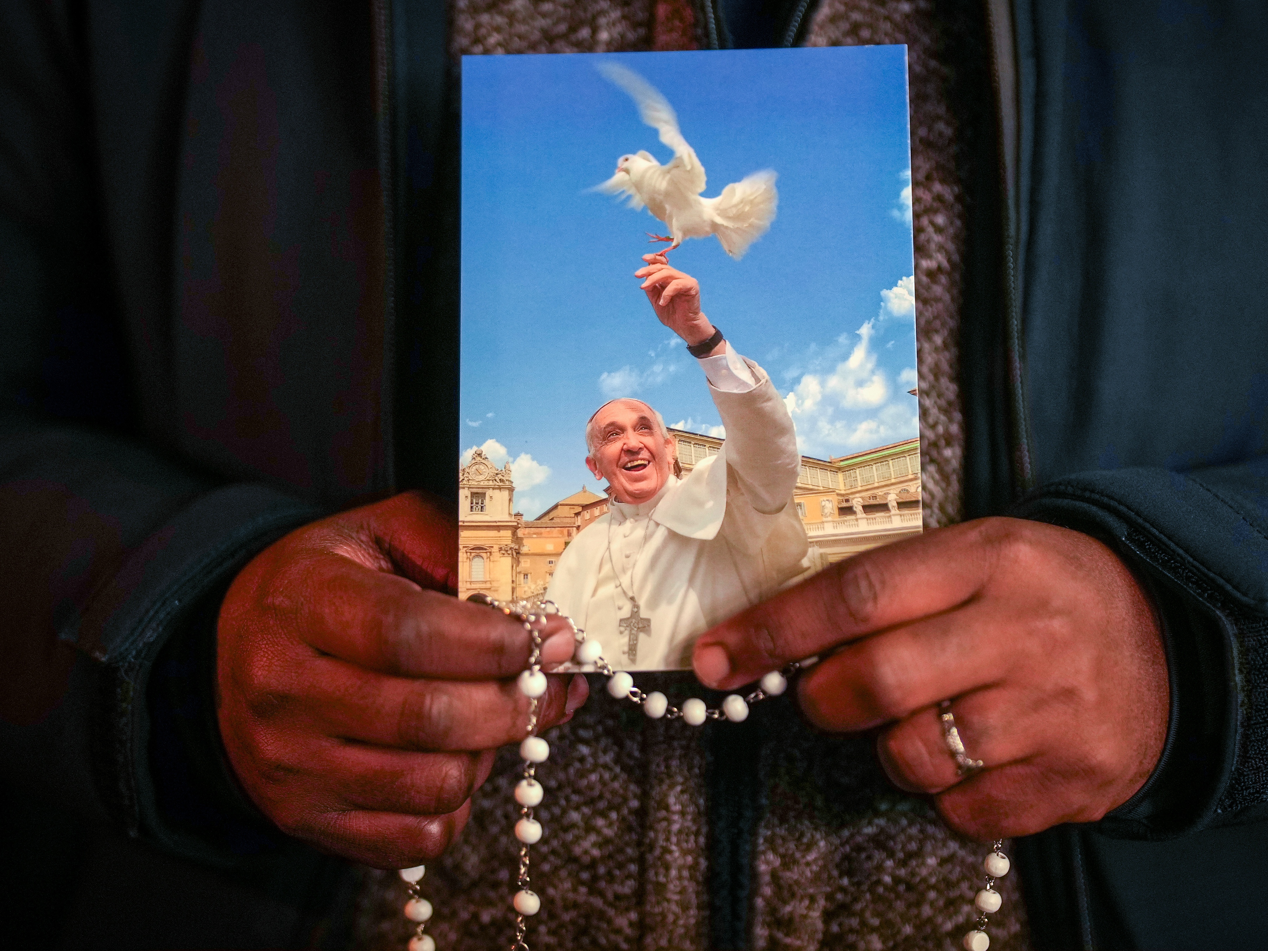 caption: A priest holds a photograph of Pope Francis during the nightly rosary prayer service in St Peter's Square on Thursday, March 6 in Vatican City.