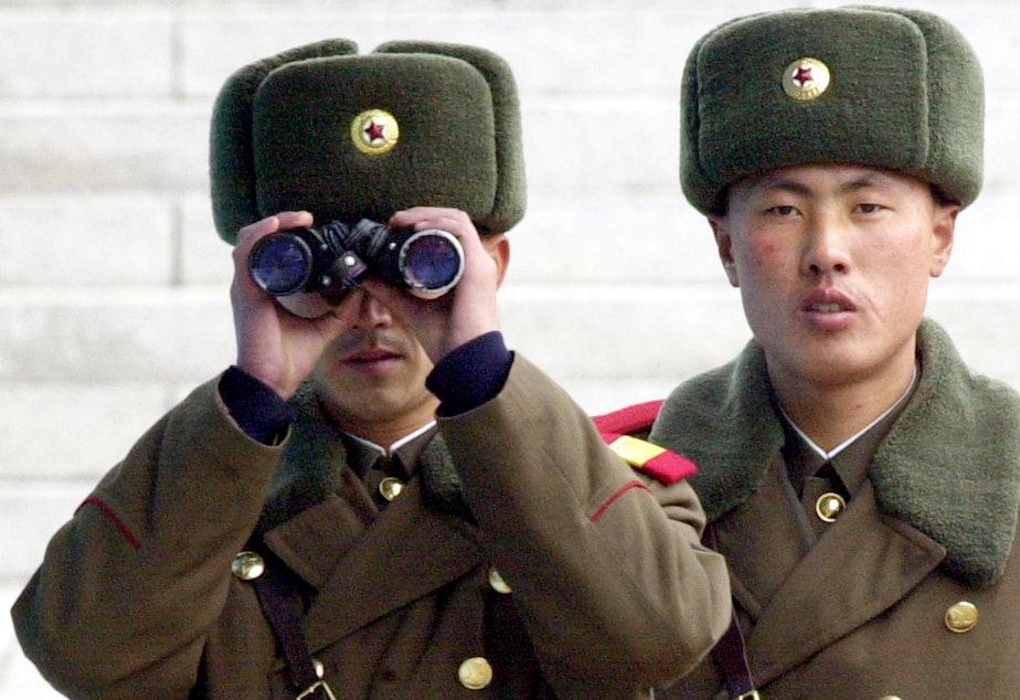 caption: A North Korean soldier looks at the southern side through a pair of binoculars at the border village of Panmunjom, north of Seoul, Wednesday, Feb. 26, 2003.