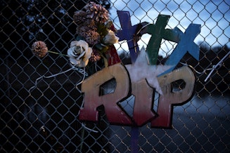 caption: A memorial with three crosses hangs on a chain-link fence along Totem Beach Road on the Tulalip Reservation on March 8, 2023.  