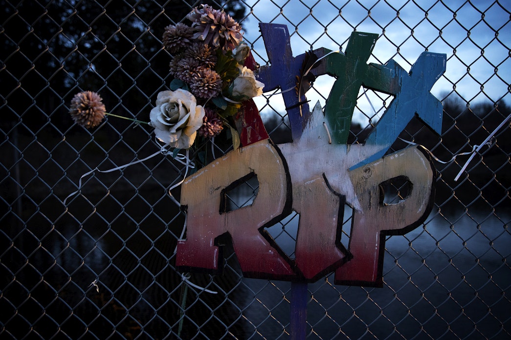 caption: A memorial with three crosses hangs on a chain-link fence along Totem Beach Road on the Tulalip Reservation on March 8, 2023.  