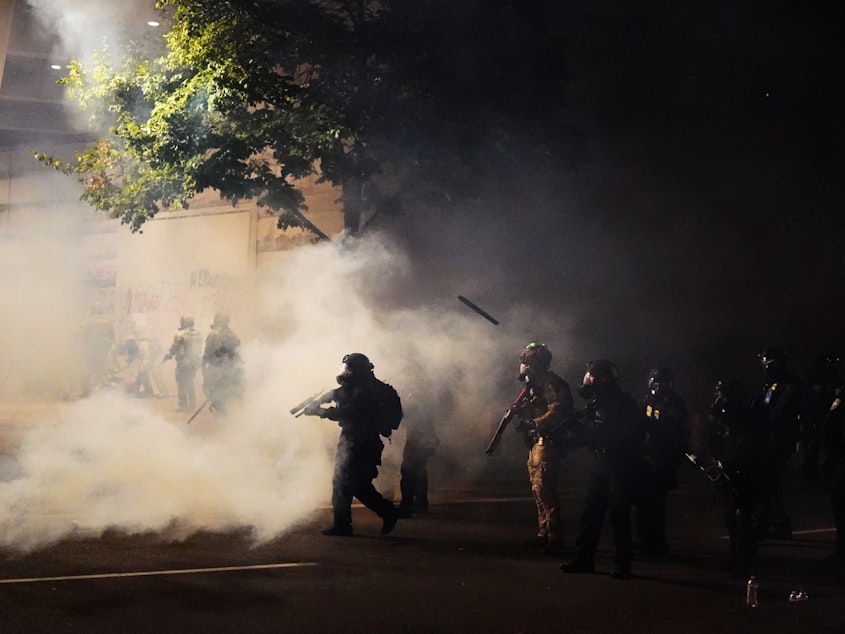 caption: Federal officers walk through tear gas while dispersing a crowd during a July 21 protest in Portland, Ore. A temporary restraining order on Thursday blocked federal agents from knowingly targeting journalists and legal observers.