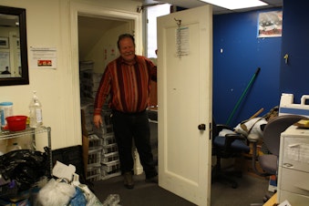 caption: Real Change field organizer Neil Lampi says the sticky door to the closet where they store unsold newspapers became so stuck they had to take it off its hinges. He says he's 'put two and two together,' and now blames the soil settlement in Pioneer Square.