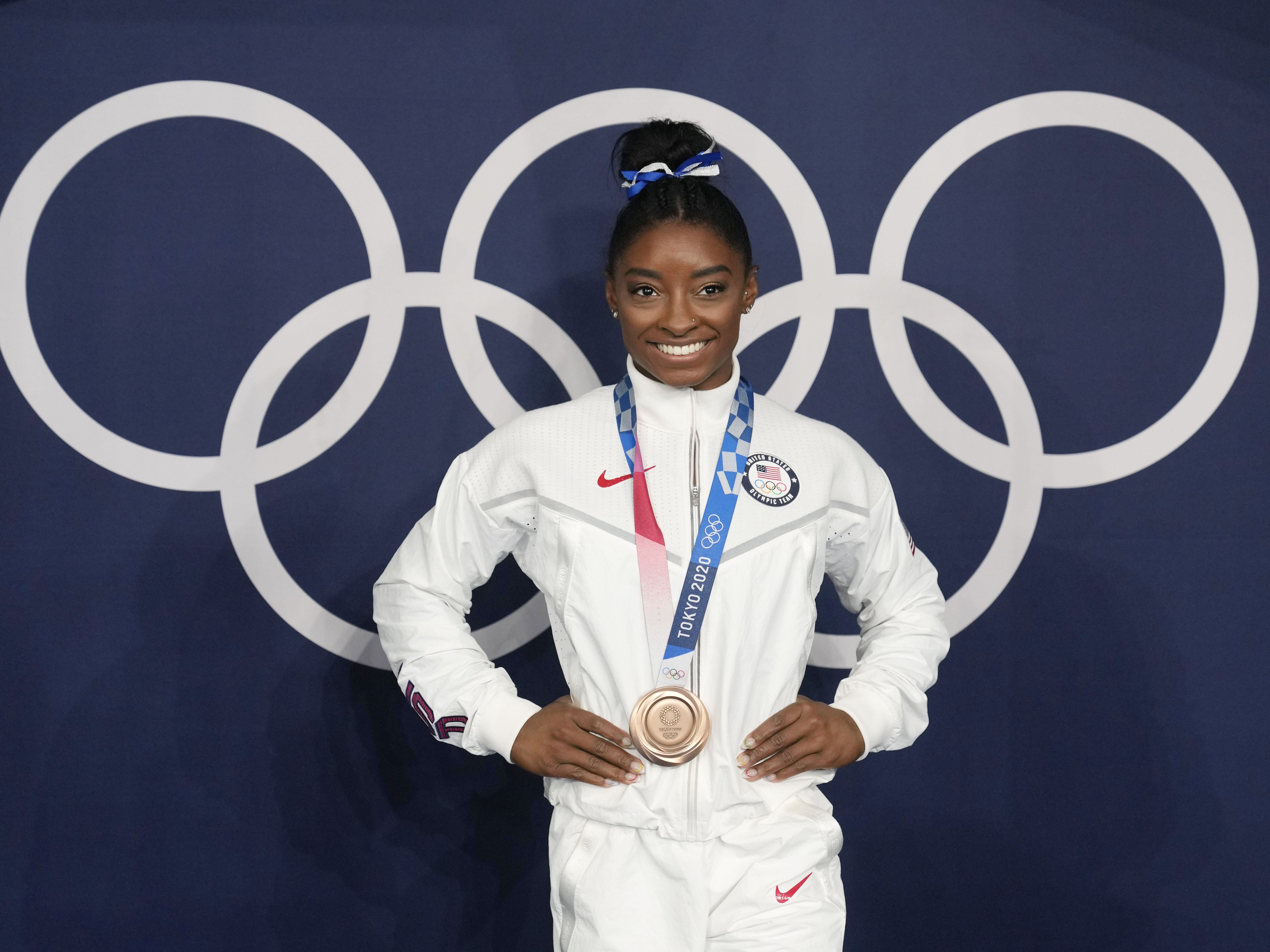 caption: Simone Biles poses wearing her bronze medal from balance beam competition during artistic gymnastics at the Summer Olympics on Aug. 3, 2021, in Tokyo. President Biden will present the Presidential Medal of Freedom to Biles and 16 others at the White House next week.