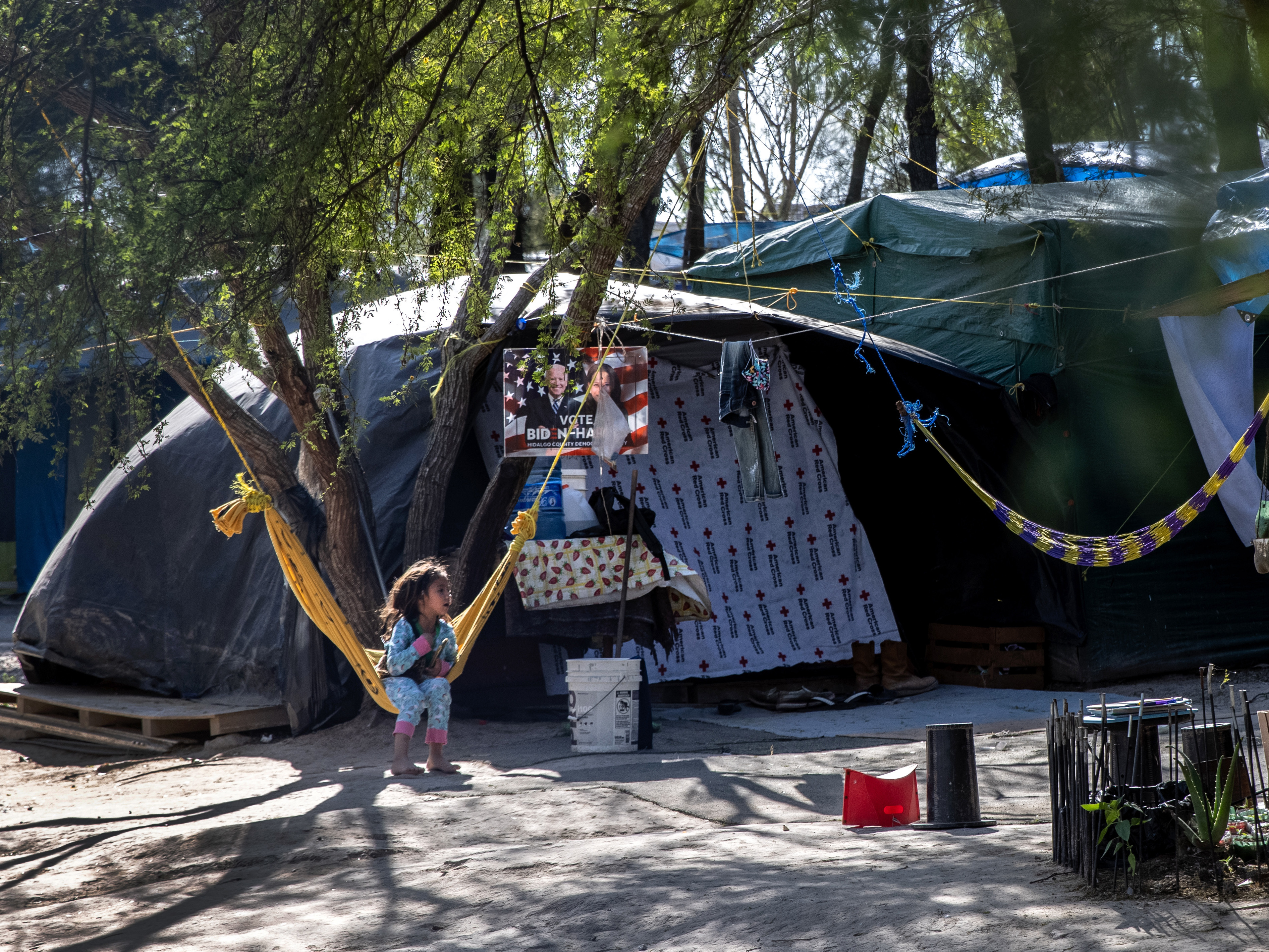 caption: A Salvadoran girl sits inside a camp for asylum-seekers on Sunday in Matamoros, Mexico, where some 600 people who left Central America have been waiting for immigration court hearings.