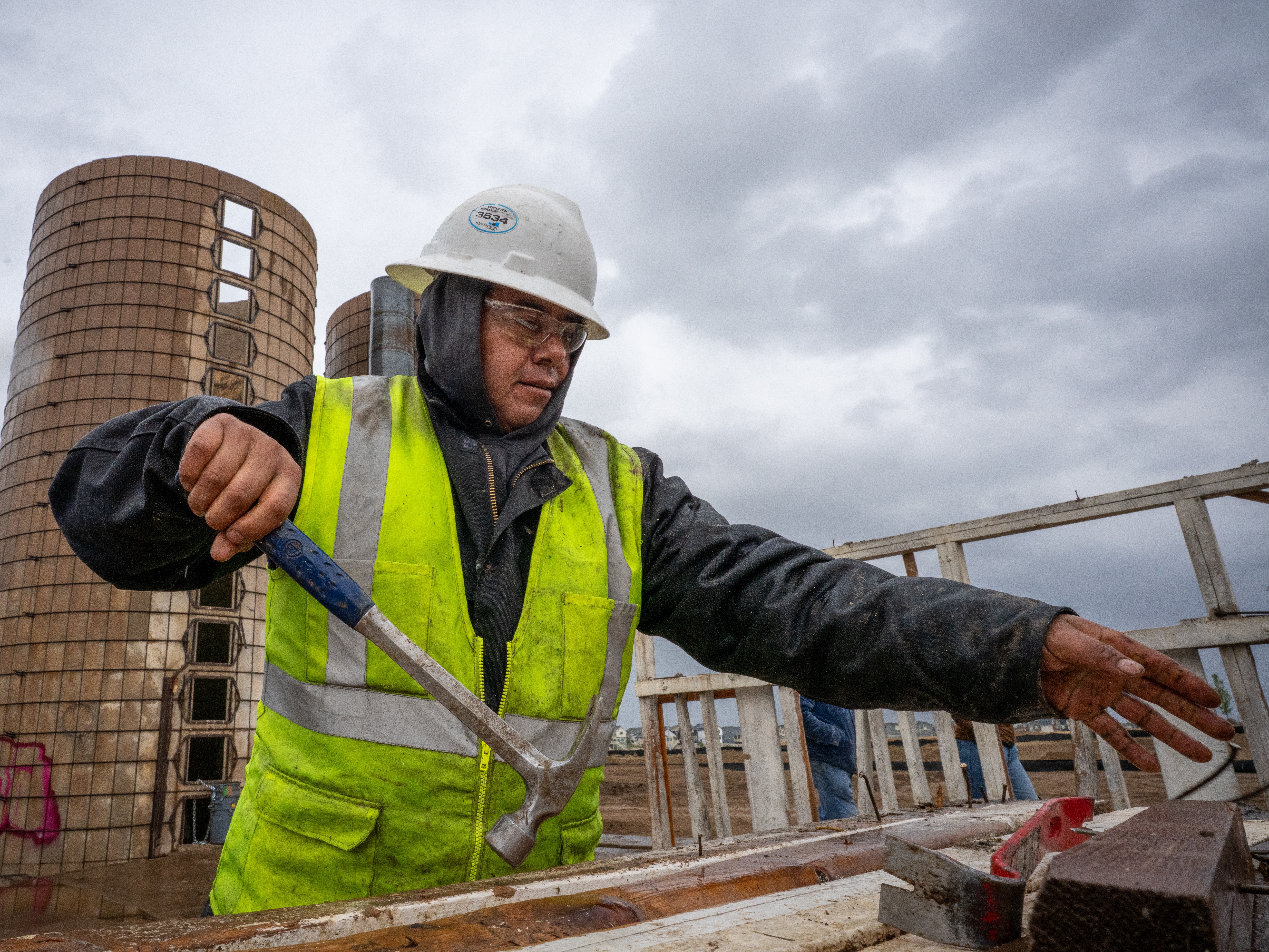 caption: On the site of a former ranch slated for housing development on the outskirts of Aurora, Colo., Pedro Macedo of Perks Deconstruction pulls nails from a wood frame that once stood in a barn.