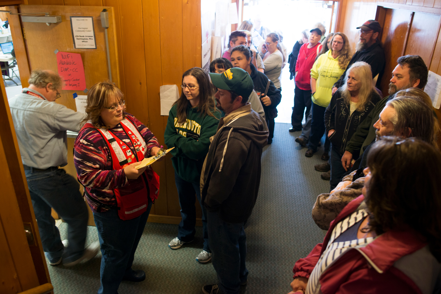 caption: In the entryway to the Darrington Community Center, Red Cross Volunteer Christine Dahl works through the list of area residents seeking gas cards to help with the cost of traveling the two and a half hour detour created by the devastating mudslide.