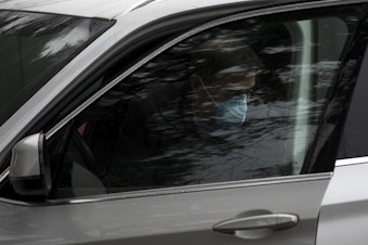 caption: A person wearing a mask arrives at the Life Care Center of Kirkland on Monday, March 2, 2020, in Kirkland.
