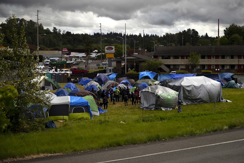 caption: Asylum seekers gather while awaiting a possible sweep of their new encampment location, in front of an empty Econo Lodge on Tuesday, June 4, 2024, in Kent. 