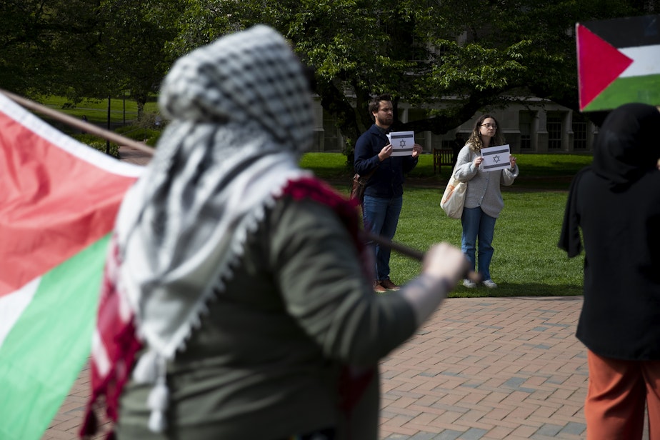 caption: Counter-protestors, including University of Washington senior Olivia Feldman, right, co-President of Students Supporting Israel, stand nearby holding printed Israeli flags as students protest at the UW Palestine Encampment on Monday, April 29, 2024, on the University of Washington campus in Seattle. 