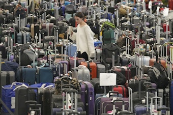 caption: A woman walks through unclaimed bags at Southwest Airlines baggage claim at Salt Lake City International Airport on Thursday, as the carrier canceled another 2,350 flights after a winter storm overwhelmed its operations days ago.