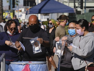 caption: People drop their test kits into a receptacle at a coronavirus testing site in the North Hollywood section of Los Angeles on Saturday. With COVID-19 cases surging at a record pace in California, Gov. Gavin Newsom has warned that the state's hospitals could soon be overwhelmed.