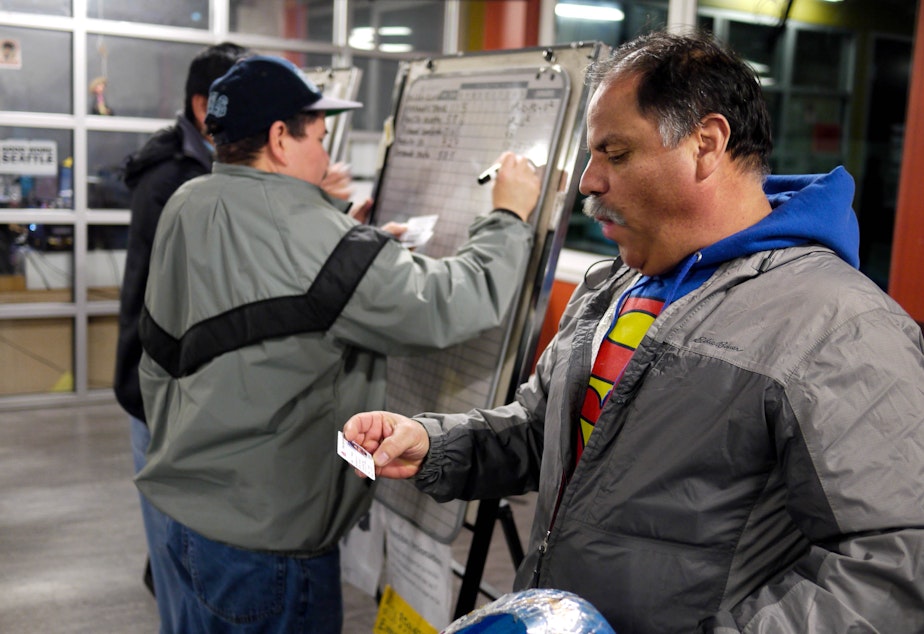 caption: Workers at Casa Latina run a morning lottery to distribute job requests for housecleaning, painting, yard work and other odd jobs.