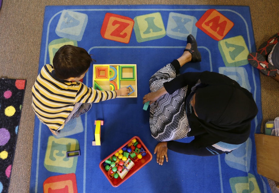 caption: Declan Hart, 4, left, and teacher-in-training Deassi Usman, right, play with shape blocks during a Pre-Kindergarten class at the Community Day Center for Children, during class Tuesday, Oct. 21, 2014, in Seattle.