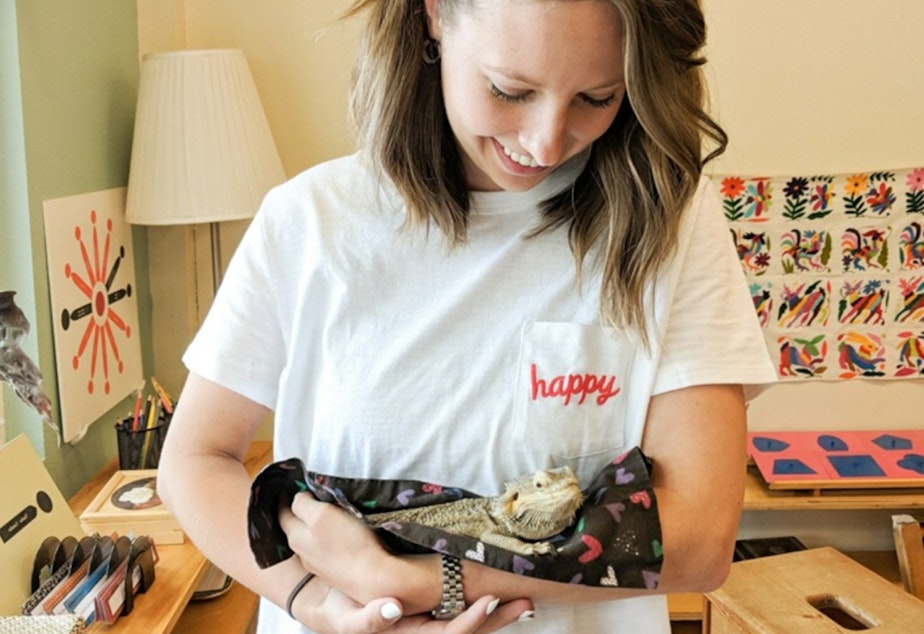 caption: Elly McCarthy in a classroom at Pacific Crest Montessori School, holding a class pet, Burnadette the Bearded Dragon! 