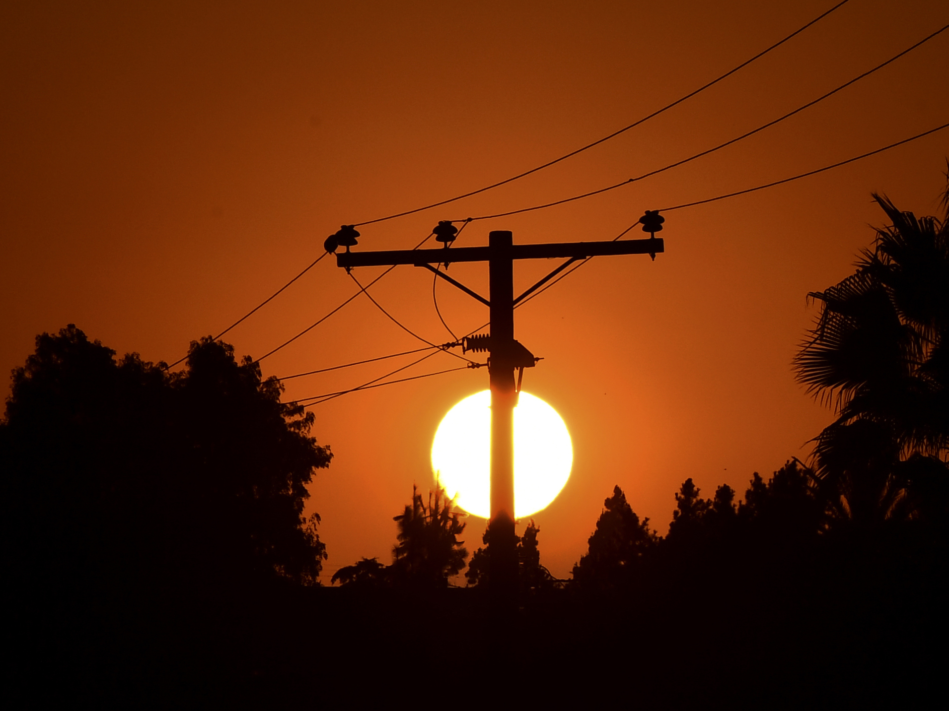caption: The sun sets behind power lines in Los Angeles in September.