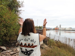 caption: Duwamish Tribal Services Executive Director Jolene Haas holds up her hands, a traditional gesture of gratitude, on the banks of the Duwamish River in Seattle on Sept. 21, 2019.