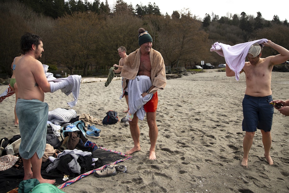 caption: KAVU employees, including owner Barry Barr, center, laugh after cold plunging in the Puget Sound on Friday, March 7, 2025, at Golden Gardens Park in Seattle.