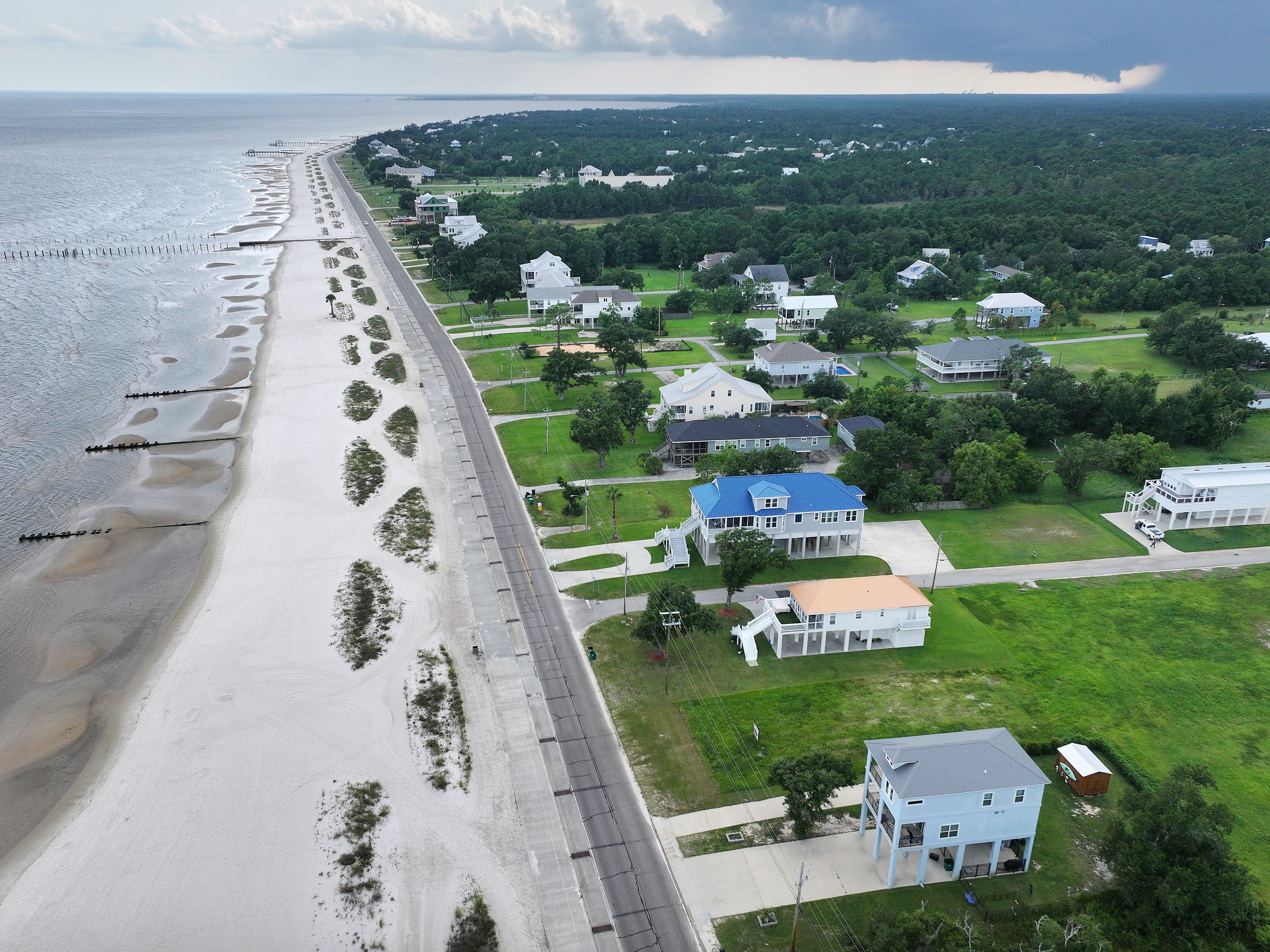 caption: An aerial view of rebuilt elevated homes earlier this month along Waveland Beach in Mississippi, an area hard-hit by Hurricane Katrina 20 years ago. The catastrophic storm sent an approximately 30-foot-high storm surge into Waveland and destroyed or damaged nearly every home in the town. Nearly 1,400 people died across the Gulf Coast, and it remains the costliest storm in U.S. history at around $200 billion in today's dollars.