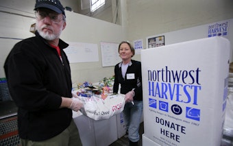 caption: Volunteers Ken Newman, right, and Caren Shepsky heft a 50-pound bag of rice at the Cherry Street Food Bank, run by Northwest Harvest, Wednesday, Nov. 11, 2009, near downtown Seattle. Northwest Harvest, a non-profit hunger relief agency, also provides food for over 300 partner programs state-wide. American charities say they have weathered about a 9 percent drop in giving this year and a recent survey show they may see a decrease in year-end generosity. 