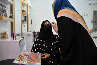 caption: An Afghan beautician applies makeup to a client at a beauty salon in Mazar-i-Sharif.