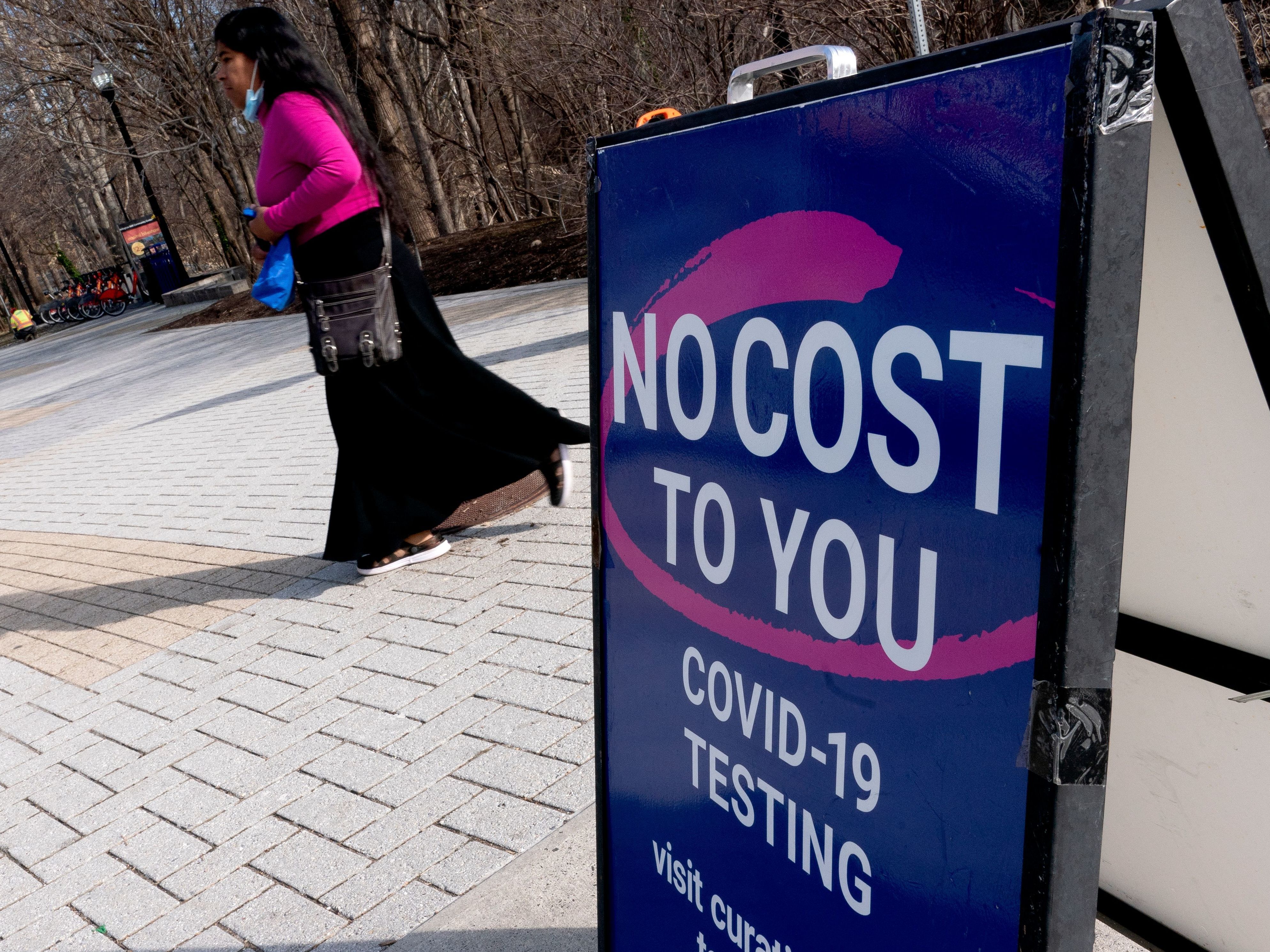 caption: A person walks past a COVID-19 testing location in Arlington, Va., on March 16. A new website launched by the Biden administration will provide a locater for test-and-treat facilities, among other services.