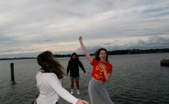 caption: Mercer Island High School graduating seniors (from left to right) Isabel Funk, Annie Poole, and Elizabeth Gottesman dance to music on a Mercer Island dock on June 8, 2020, the evening before graduation. Instead of a senior graduation party, attended by many, these seniors spent the time together as a smaller group. 