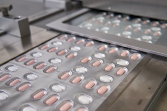 caption: Paxlovid tablets are packaged at a Pfizer factory.