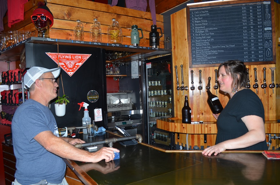 caption: Flying Lion Brewing manager Sara McCabe serves a customer on reopening day, June 30.