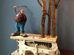 caption: Artist Don Becker creates automatons after being laid off from his job during the pandemic. This mechanical sculpture features a woodcutter being thwarted by trees.