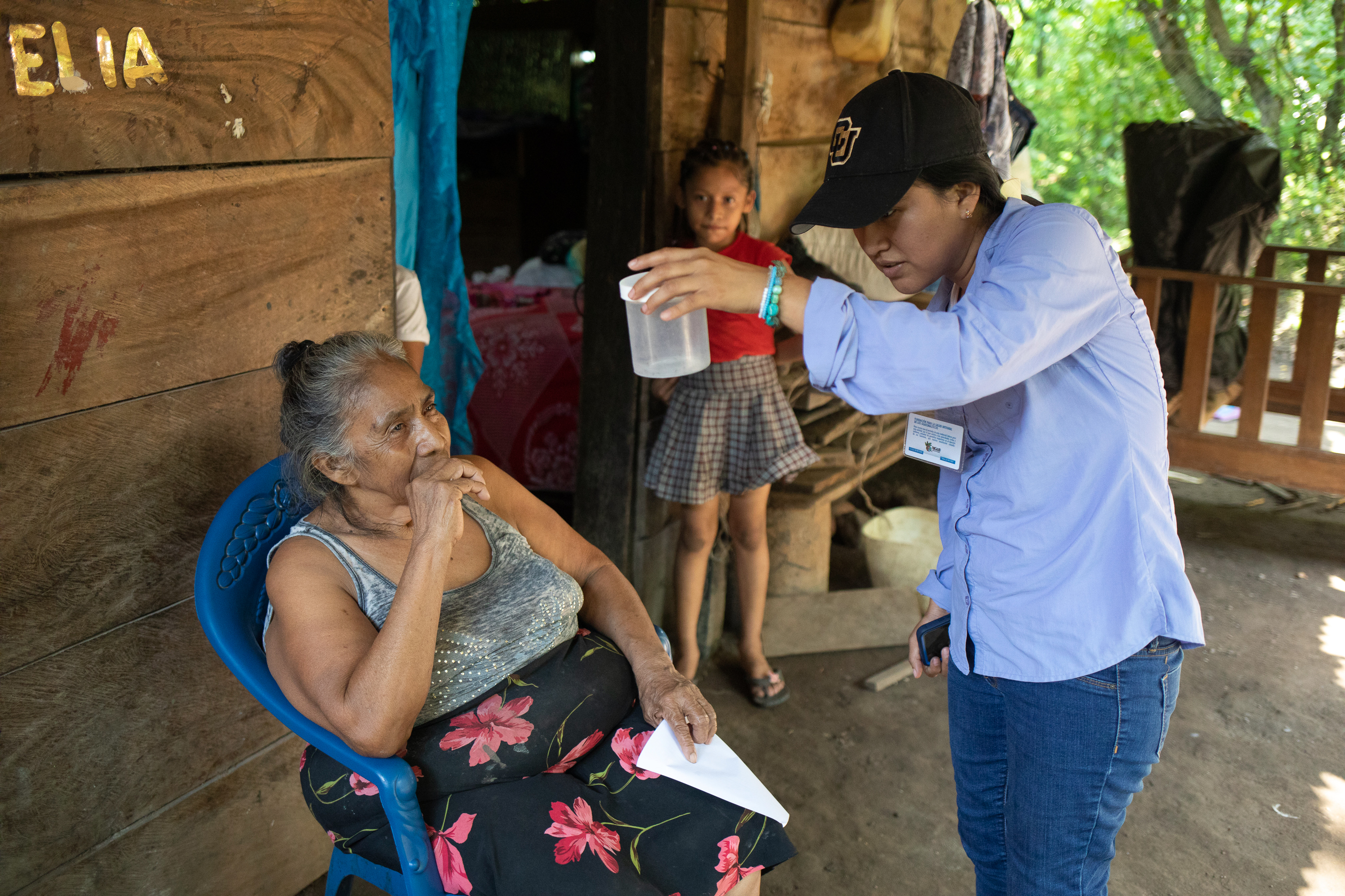 caption: Neudy Rojop (right) shows Eduviges Lopez the mosquitoes trapped in her home by the insectazooka in Los Encuentros, Guatemala.