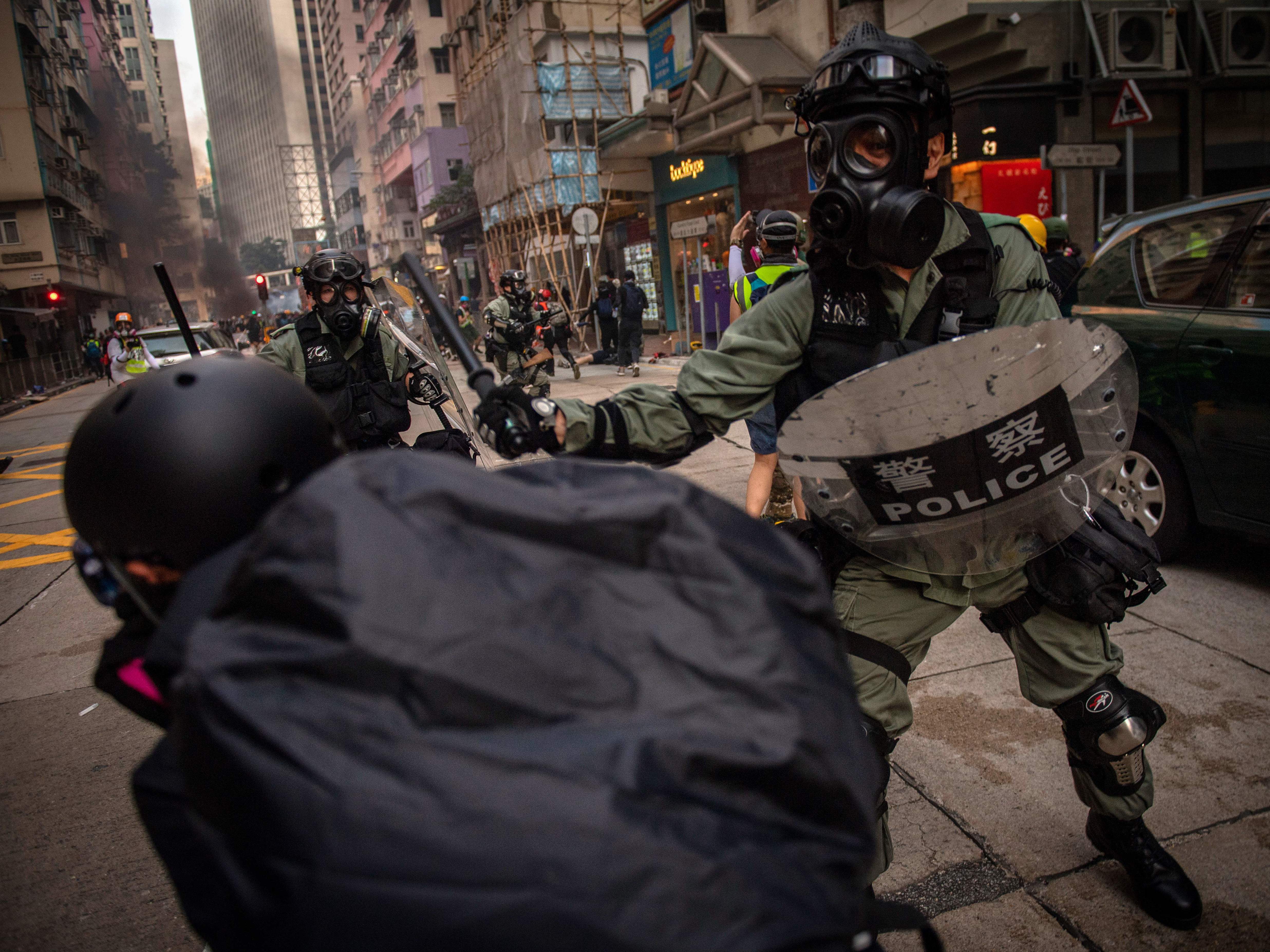 caption: Police try to stop a protester in the street in the Wanchai area in Hong Kong on Oct. 1, as the city observes the National Day holiday to mark the 70th anniversary of communist China's founding.