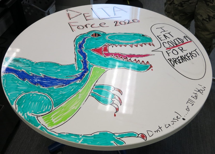 caption: The Delta team's "morale board" is a play on the time-honored military tradition of "morale patches," inside jokes on patches, but adapted to a dry-erase office table. 