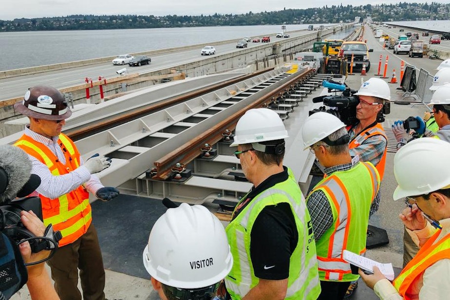 caption: Sound Transit's John Sleavin explains to Seattle media outlets how rails will be installed across the I-90 floating bridge